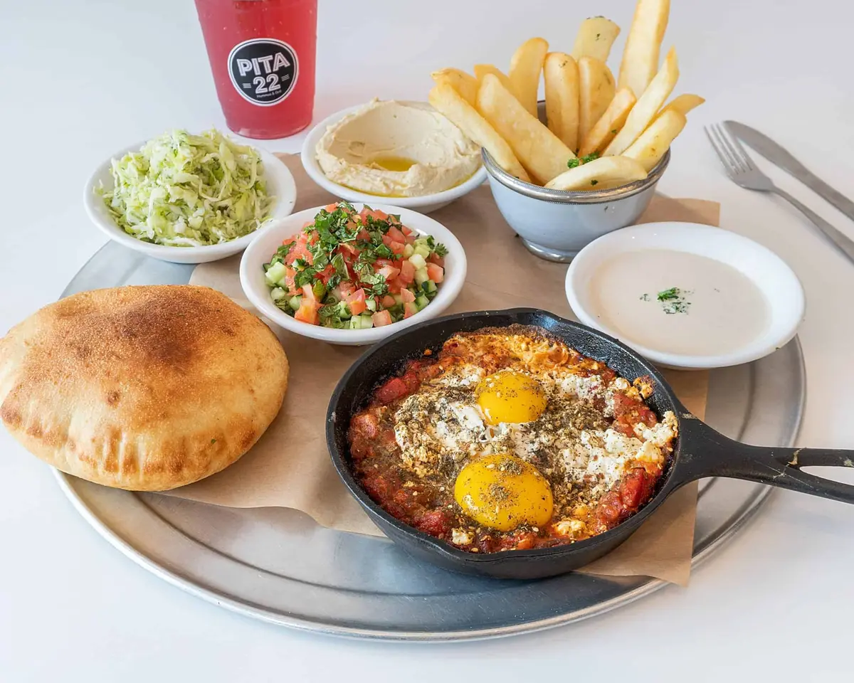 Shakshuka: poached eggs in roasted tomato and pepper sauce, with hummus and pita