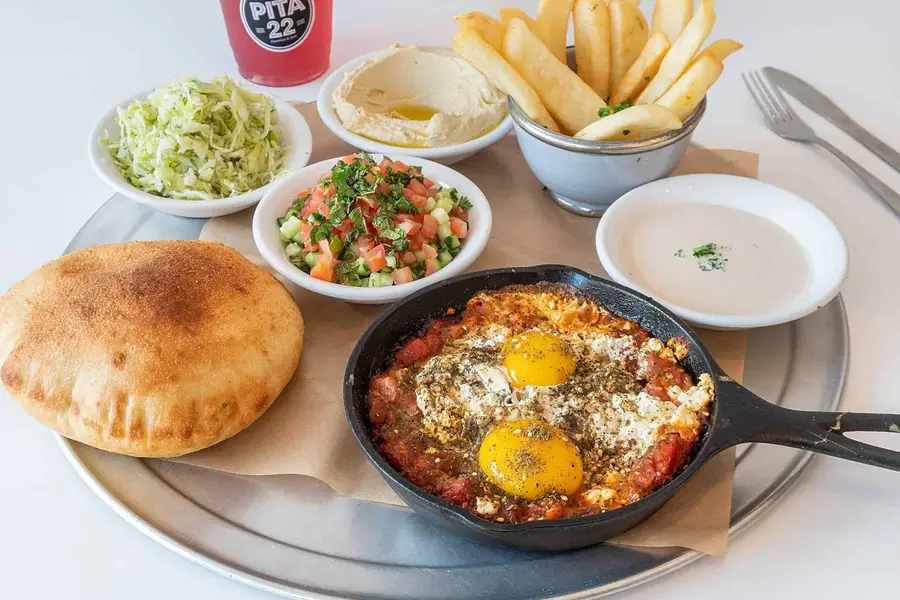 Shakshuka plate with poached eggs, hummus and pita